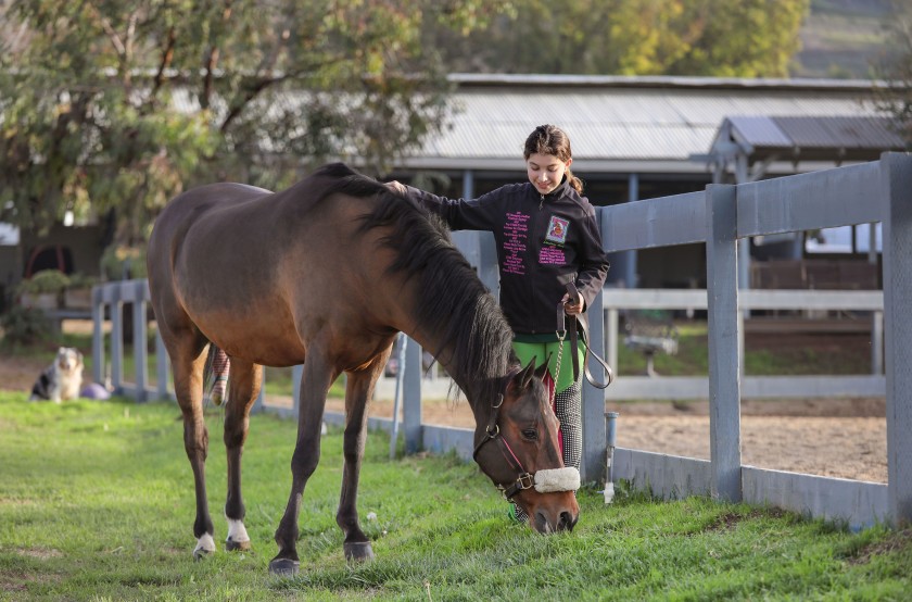December 11, 2019, Escondido, California_USA_| Lindsay Heliker walks with her horse named Odyssey as he eats the fresh grass at Miller Equestrian Services. |_Photo Credit: Photo by Charlie Neuman(Charlie Neuman/Photo by Charlie Neuman) December 11, 2019, Escondido, California_USA_| Lindsay Heliker walks with her horse named Odyssey as he eats the fresh grass at Miller Equestrian Services. |_Photo Credit: Photo by Charlie Neuman(Charlie Neuman/Photo by Charlie Neuman)