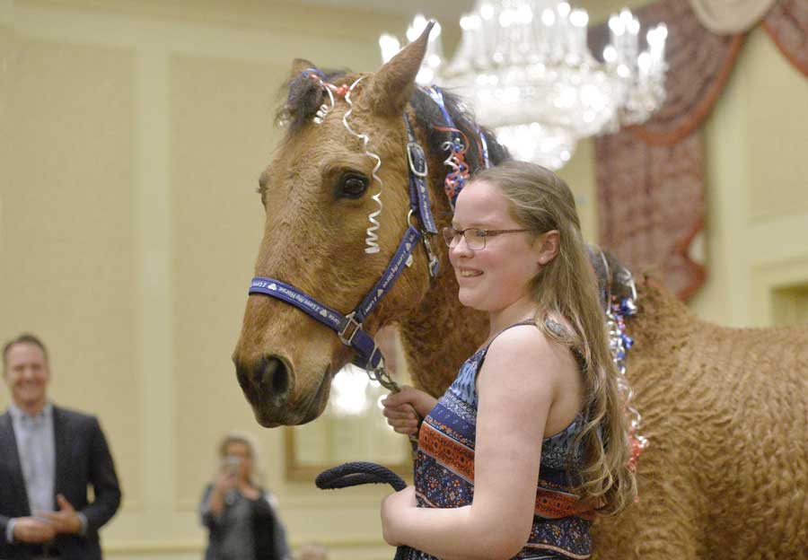 Carly Dahlkemper, 12, left, thanks Denise Olczak, executive director of Mystic Mountain Training Center, for helping grant her wish of horse Emmy during a Make-A-Wish Greater Pennsylvania and West Virginia event inside the Ambassador Center ballroom in Summit Township on Wednesday. Dahlkemper, who also received riding gear, has been riding Emmy at the center and has created a bond with the animal. Diagnosed with a respiratory and digestive disorder, she said she was surprised to learn that her wish had been granted. [GREG WOHLFORD/ERIE TIMES-NEWS]