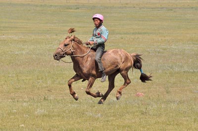 A child jockey at full gallop during a Naadam race. Many children ride these 28 -32 kilometre races without saddle and often without shoes. A child jockey at full gallop during a Naadam race. Many children ride these 28 -32 kilometre races without saddle and often without shoes.