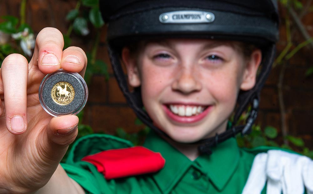 Abi Evans holds a gold quarter sovereign which features a portrait of Queen Elizabeth II on horseback during the launch of the coin with the Horse Rangers Association, at the Royal Mews in Hampton Court, Surrey. Photo credit: Steven Paston/Press Association. Abi Evans holds a gold quarter sovereign which features a portrait of Queen Elizabeth II on horseback during the launch of the coin with the Horse Rangers Association, at the Royal Mews in Hampton Court, Surrey. Photo credit: Steven Paston/Press Association.