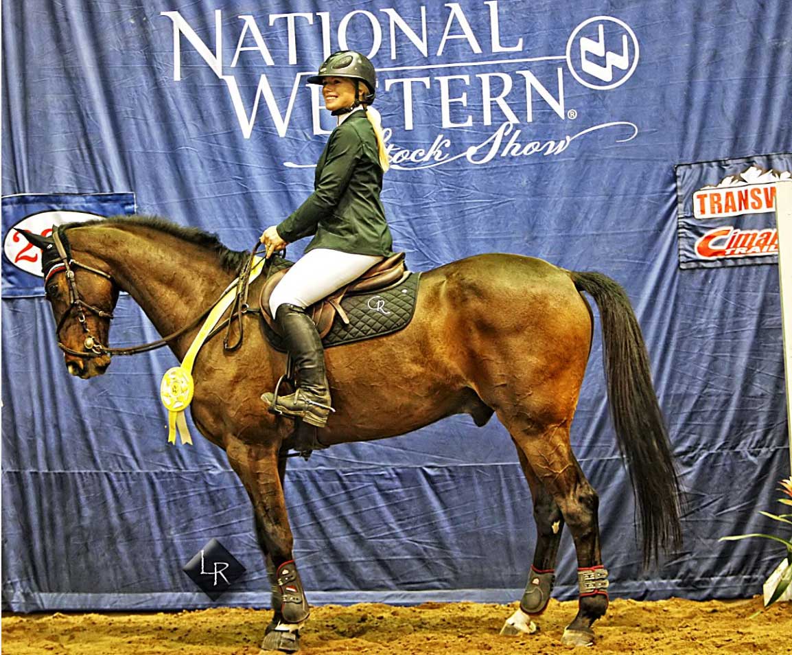 Twenty-three-year-old Carly Ramsey posed with her third place ribbn after the $40,000 NWSS Grand Prix on Jan. 20, 2020. In her first NWSS, the Texas-based horse trainer successfully competed in the highest profile jumping events at the historic venue. Ramsey is not only an accomplished showjumper, but she also cometitions and titles as a ranch bronc rider. Photo by Lincoln Rogers